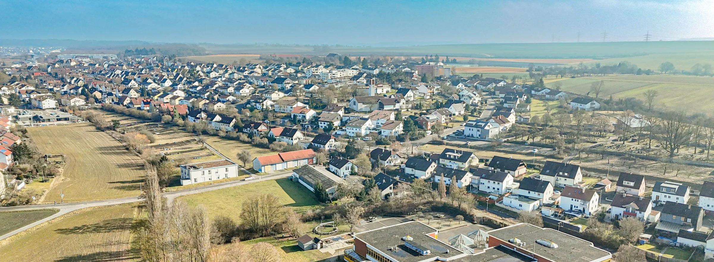Luftaufnahme von Kleinglattbach mit Wohngebiet, Kirchturm, Schule und angrenzenden Feldern